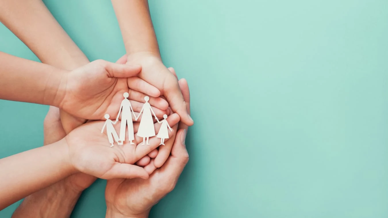 Mãos a proteger figuras de família em papel, simbolizando parentalidade, proteção e desenvolvimento infantil — MindRise